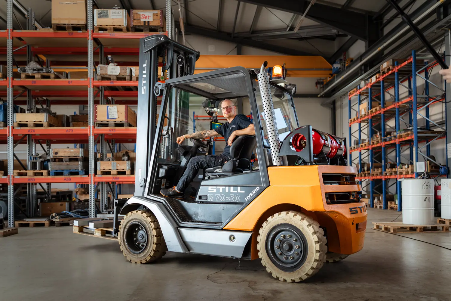 Gabelstaplerfahrer arbeitet in einer Lagerhalle mit Regalen und Paletten.