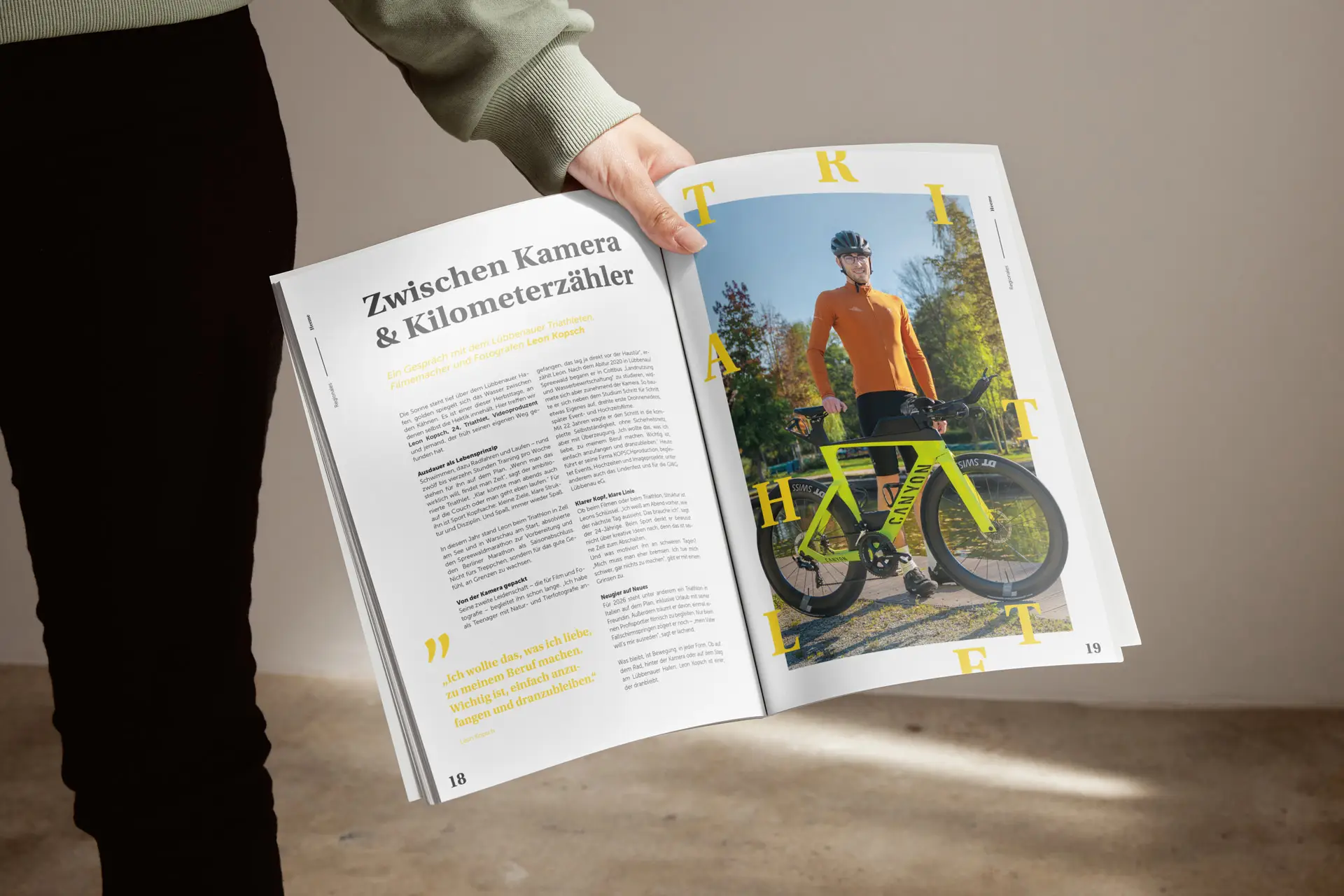 Person hält ein aufgeschlagenes Magazin in der Hand. Auf der rechten Seite ist ein Radfahrer mit Rennrad im Freien abgebildet, links ein Artikel mit der Überschrift ‚Zwischen Kamera & Kilometerzähler.